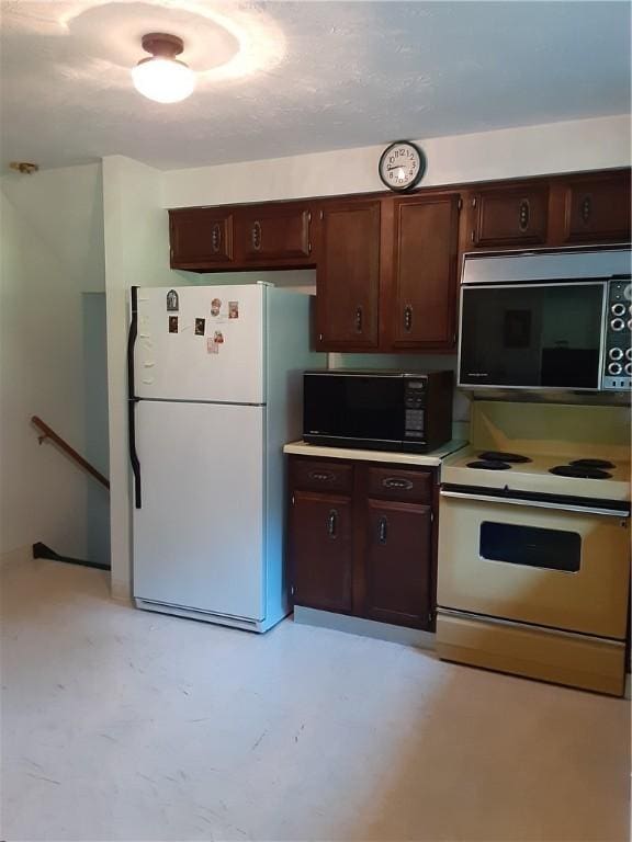 kitchen with dark brown cabinetry, white appliances, concrete floors, and light countertops