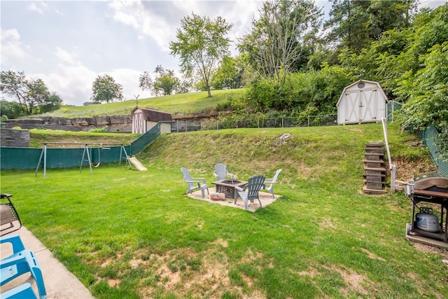 view of yard with a playground, a storage unit, and an outdoor fire pit