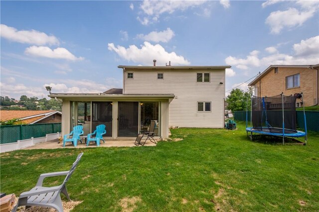 rear view of property featuring a patio area, a sunroom, a yard, and a trampoline