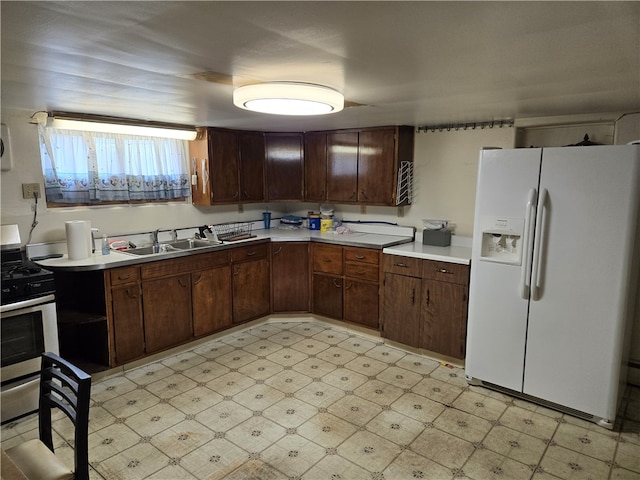 kitchen featuring white refrigerator with ice dispenser, dark brown cabinets, light tile patterned floors, and stainless steel gas stove