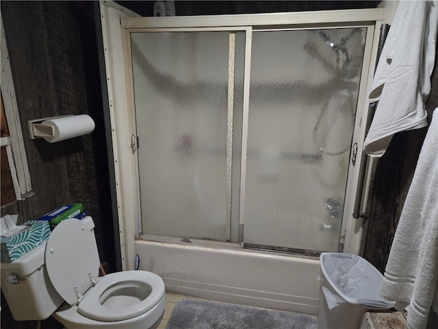 bathroom featuring shower / bath combination with glass door and toilet