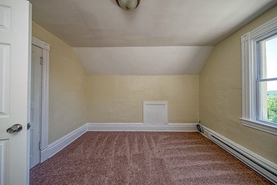 bonus room with a baseboard radiator, carpet flooring, and vaulted ceiling