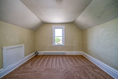 additional living space with baseboard heating, lofted ceiling, and carpet floors