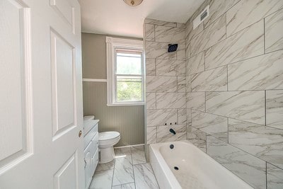 full bathroom featuring tiled shower / bath combo, vanity, tile patterned flooring, and toilet