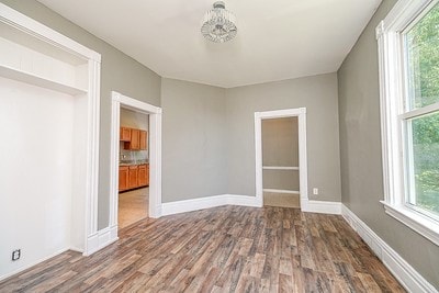 empty room with hardwood / wood-style floors, plenty of natural light, and an inviting chandelier