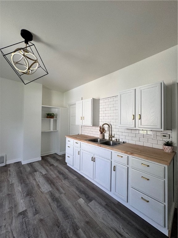 kitchen featuring dark hardwood / wood-style floors, sink, butcher block counters, and hanging light fixtures