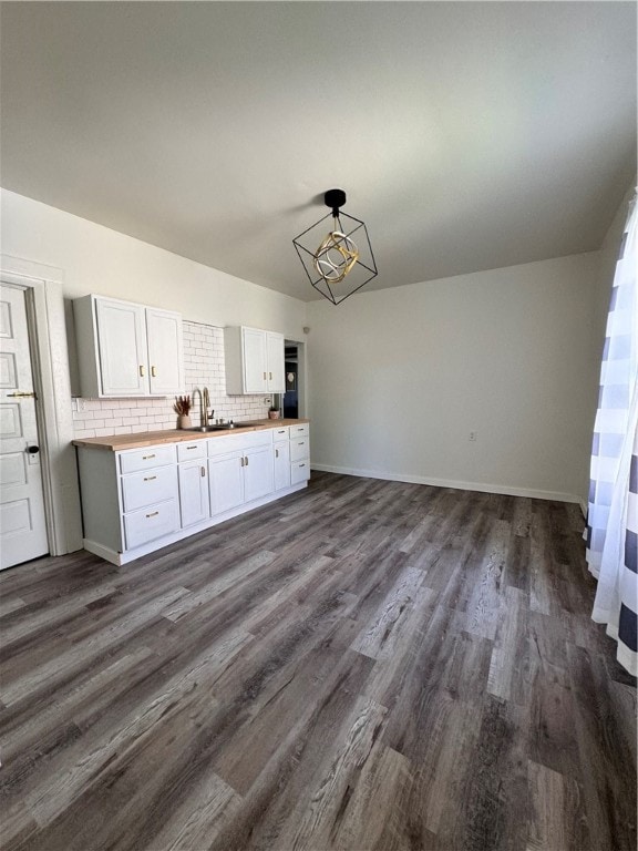 kitchen featuring pendant lighting, backsplash, sink, white cabinets, and hardwood / wood-style floors