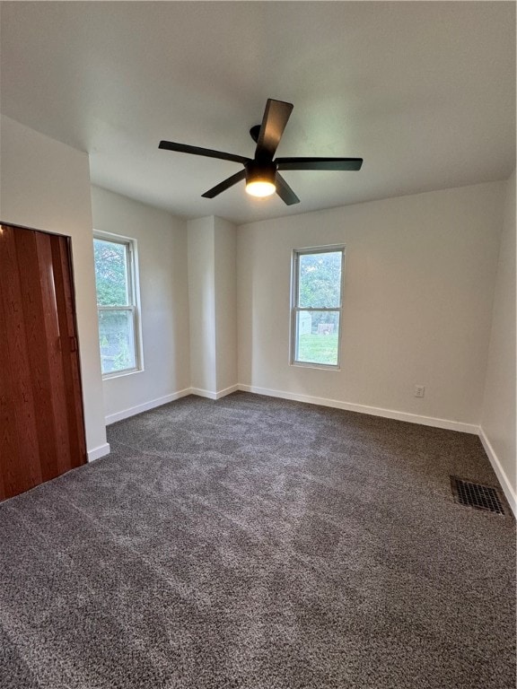 interior space featuring ceiling fan, multiple windows, and carpet