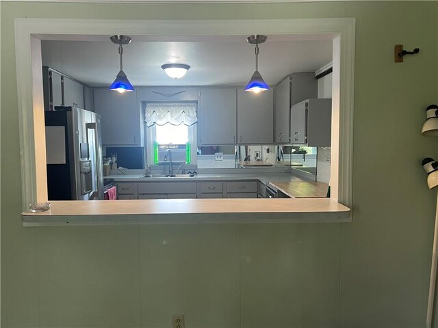 kitchen featuring stainless steel fridge, sink, and pendant lighting