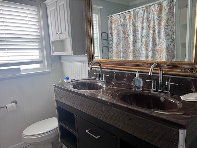 bathroom featuring dual vanity and toilet