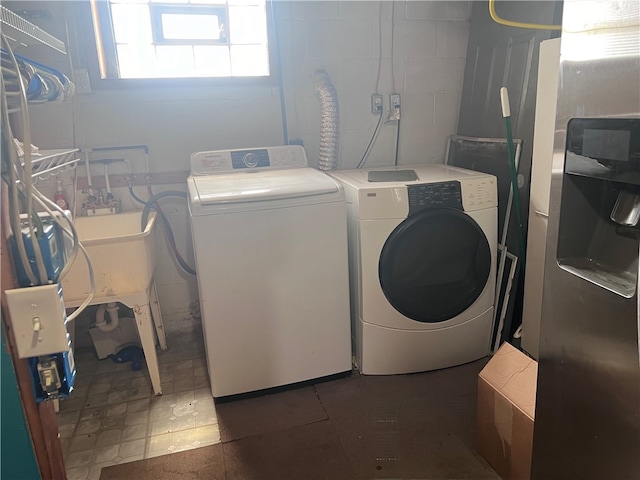 laundry area featuring sink, dark tile patterned flooring, and washing machine and clothes dryer