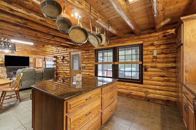 kitchen with beam ceiling, a center island, log walls, dark stone countertops, and wood ceiling