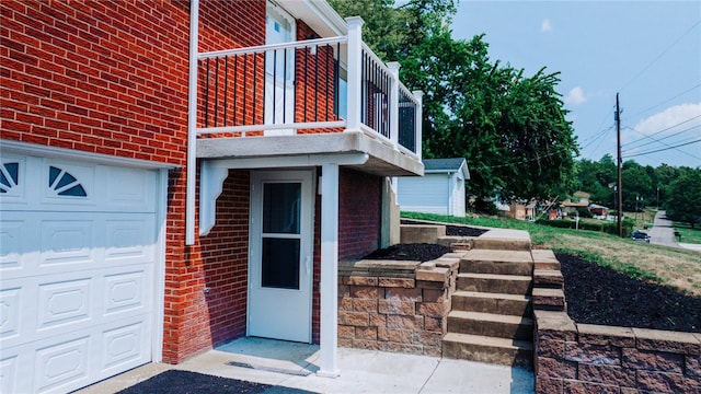 view of exterior entry featuring a garage and a balcony