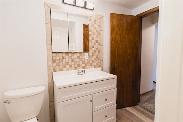 bathroom with tile walls, toilet, vanity, and hardwood / wood-style floors