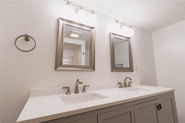 bathroom with double sink vanity and a textured ceiling