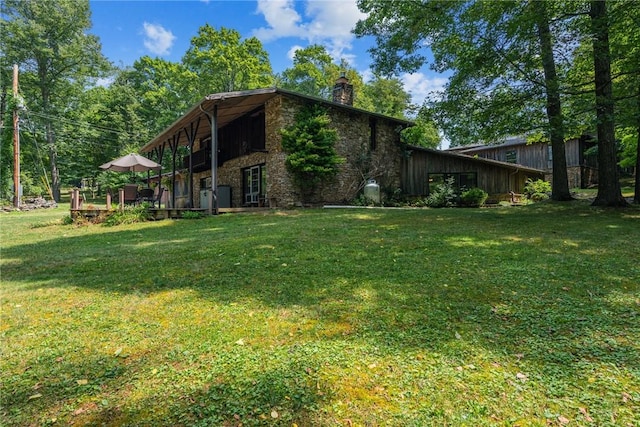 view of home's exterior with stone siding, a lawn, and a chimney