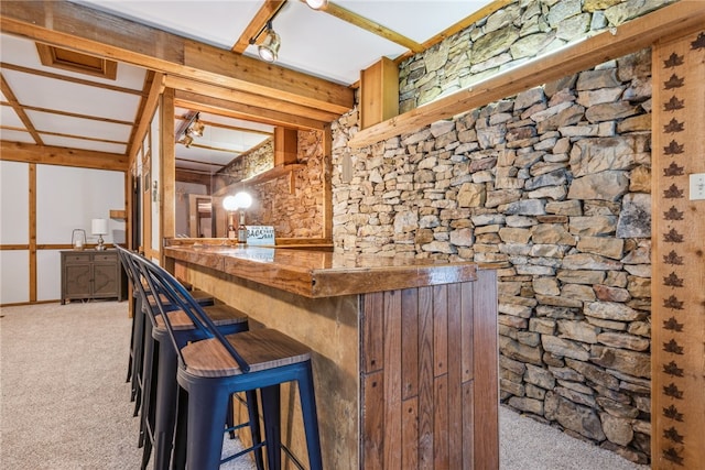 bar featuring beamed ceiling and light colored carpet