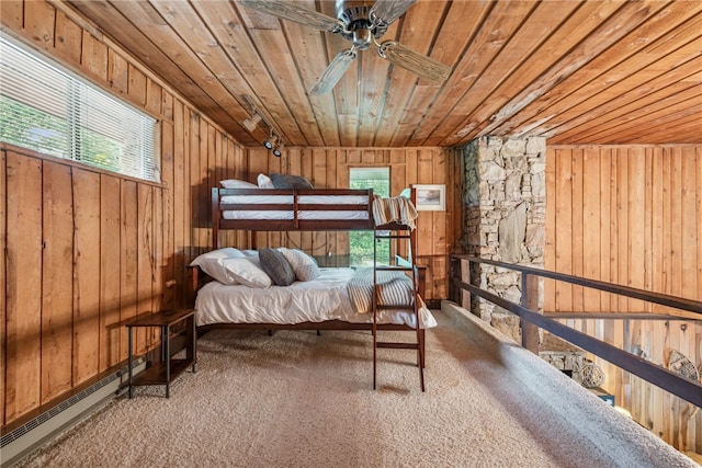 carpeted bedroom featuring baseboard heating, wooden ceiling, and wood walls