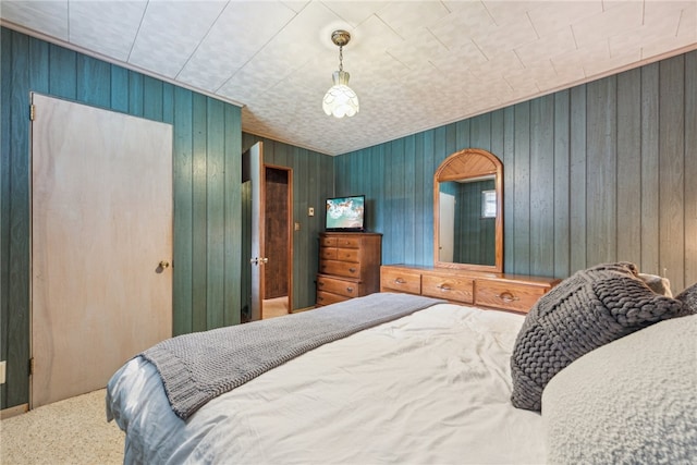 carpeted bedroom featuring wood walls