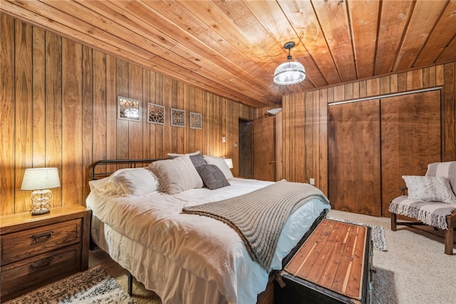 bedroom with wooden ceiling, wooden walls, a closet, and carpet floors