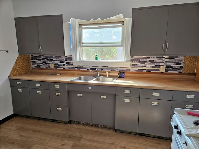 kitchen with light hardwood / wood-style floors, backsplash, sink, and gray cabinetry