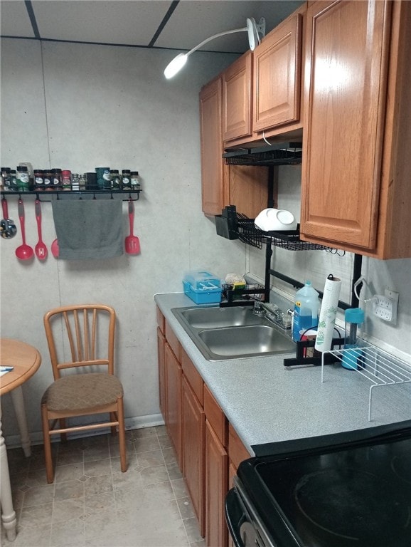 kitchen featuring light tile patterned floors, stove, a paneled ceiling, and sink