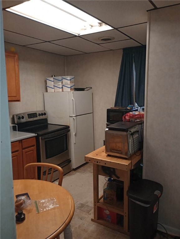 kitchen featuring a paneled ceiling, stainless steel range with electric stovetop, and white fridge