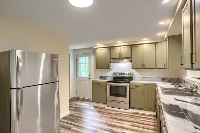 kitchen with light hardwood / wood-style flooring, light stone counters, green cabinets, stainless steel appliances, and sink