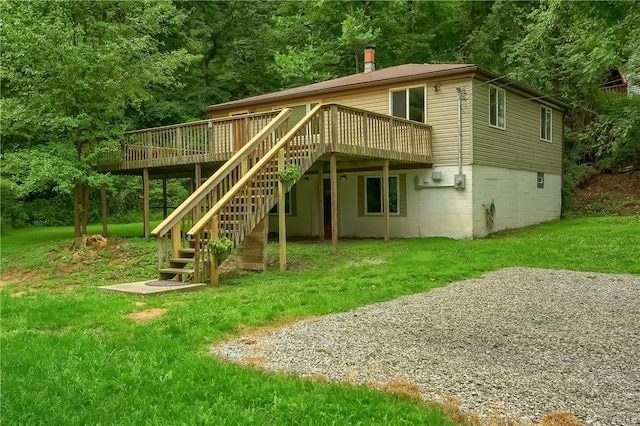 rear view of property featuring a wooden deck and a lawn