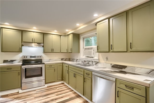 kitchen with green cabinets, light wood-type flooring, stainless steel appliances, and sink