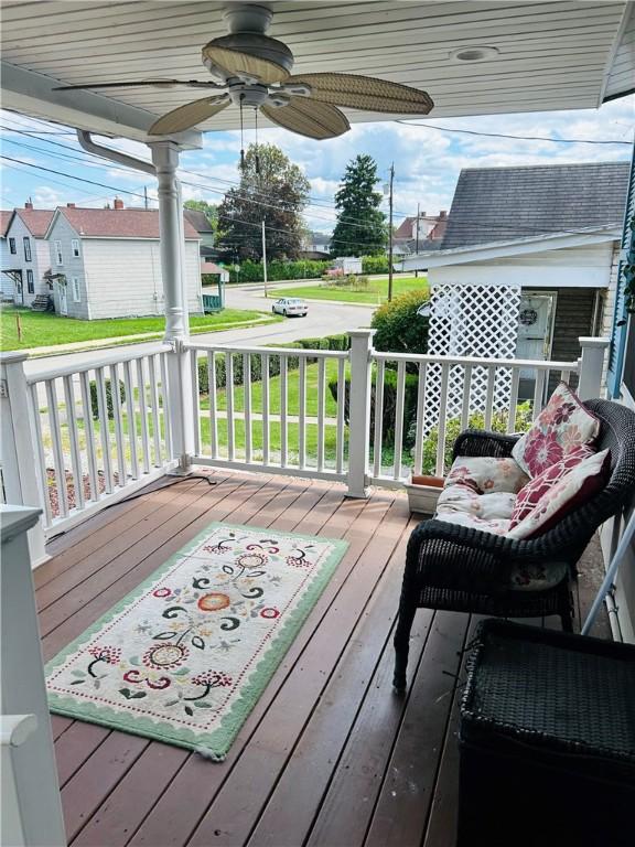 wooden deck with a residential view, a porch, and a ceiling fan