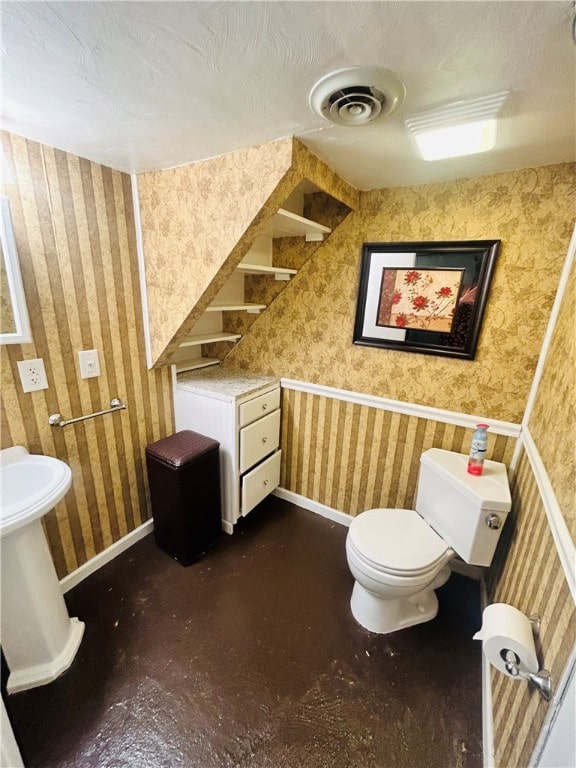 bathroom featuring a textured ceiling, toilet, and concrete flooring