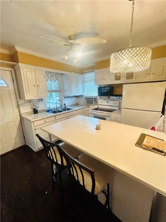 kitchen featuring white appliances, a breakfast bar, hanging light fixtures, white cabinetry, and sink