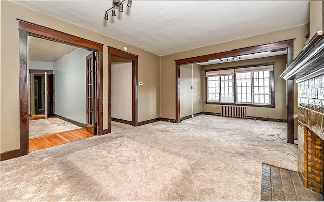 unfurnished living room with carpet, radiator heating unit, and a fireplace