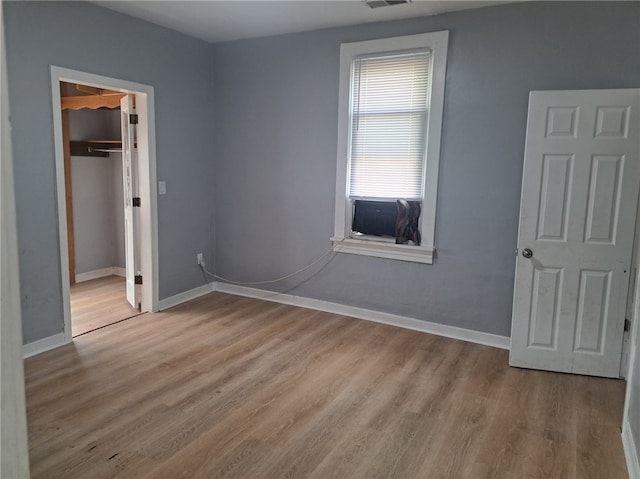 unfurnished bedroom with a closet, light wood-type flooring, and a spacious closet