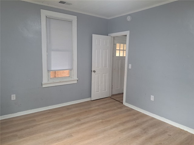 empty room with light hardwood / wood-style floors and crown molding