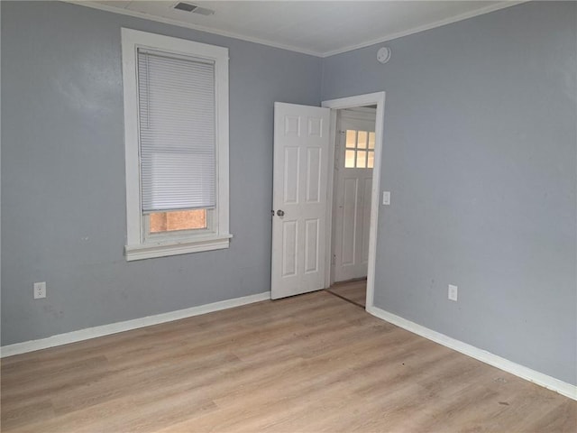 spare room featuring crown molding and light hardwood / wood-style floors