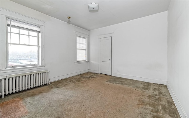 spare room featuring carpet and radiator heating unit