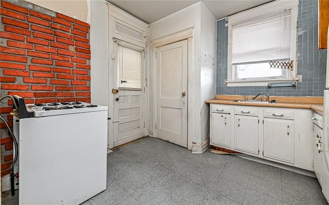 kitchen featuring white gas stove, white cabinetry, and sink