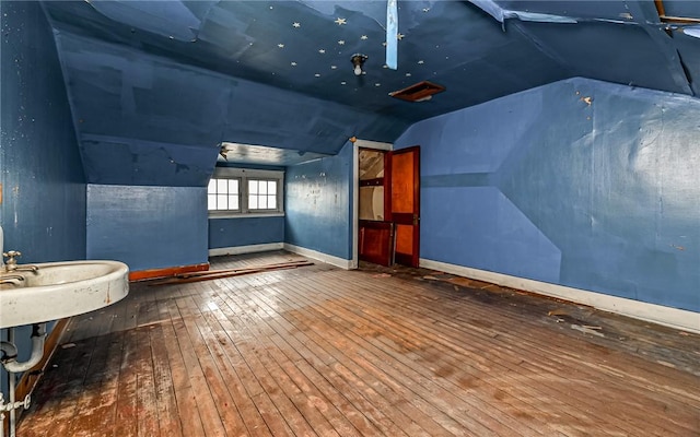 additional living space with hardwood / wood-style flooring and lofted ceiling