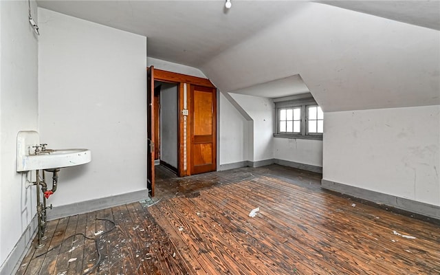 additional living space featuring sink, lofted ceiling, and dark wood-type flooring