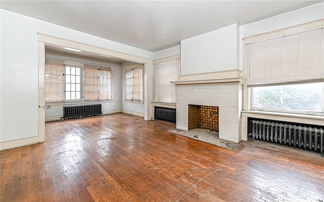 unfurnished living room with hardwood / wood-style flooring, a fireplace, and radiator