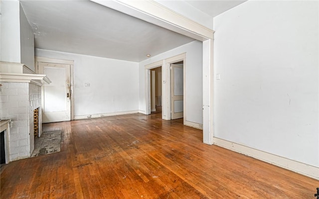 unfurnished living room featuring hardwood / wood-style floors and a brick fireplace