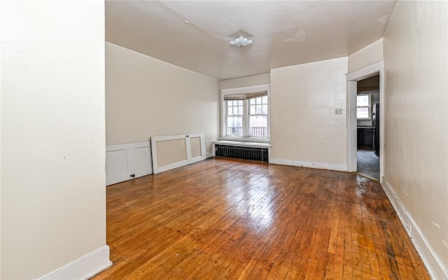 empty room with radiator heating unit and wood-type flooring