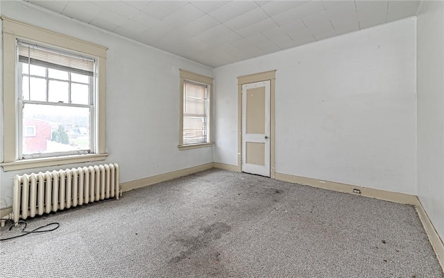 carpeted empty room featuring radiator heating unit