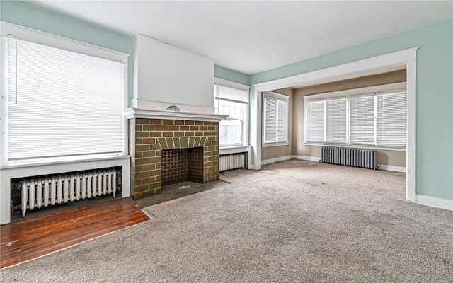 unfurnished living room featuring carpet flooring, radiator heating unit, and a fireplace