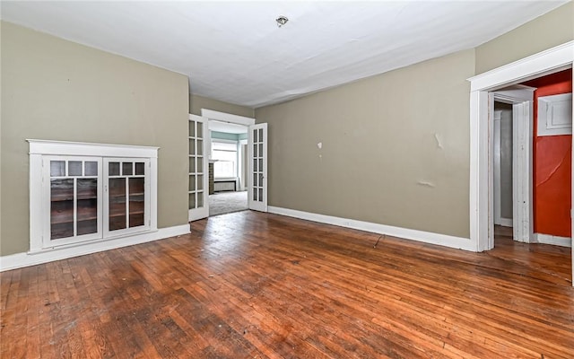 unfurnished living room with wood-type flooring and french doors