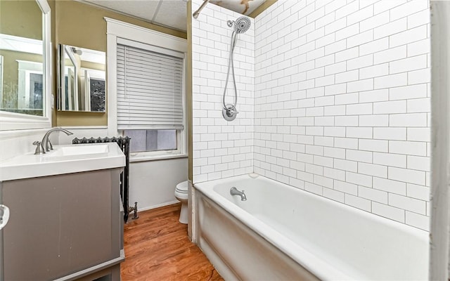 full bathroom featuring hardwood / wood-style floors, vanity, toilet, and tiled shower / bath combo