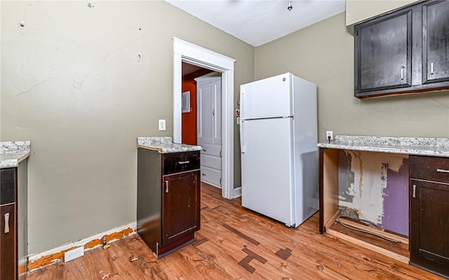 kitchen with white refrigerator, dark brown cabinetry, and light hardwood / wood-style flooring