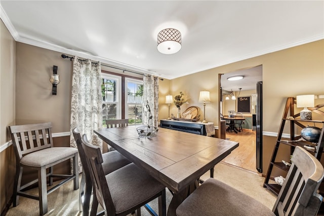 dining area with ornamental molding and light hardwood / wood-style floors